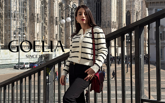 A lady wears a striped cardigan and black pants.