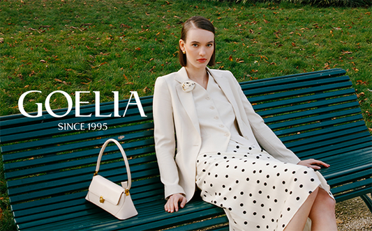 A lady wearing a blazer is sitting on the bench.