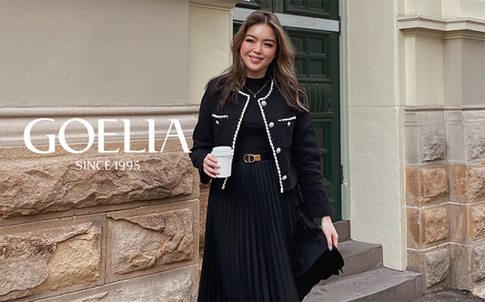 A lady wears a black tweed jacket.