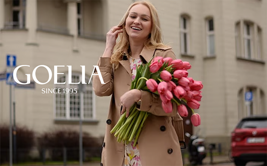 a lady wears a trench coat holding pink flowers 