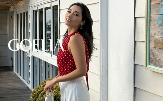 a lady in a red off the shoulder top and a pair of wide leg white pants